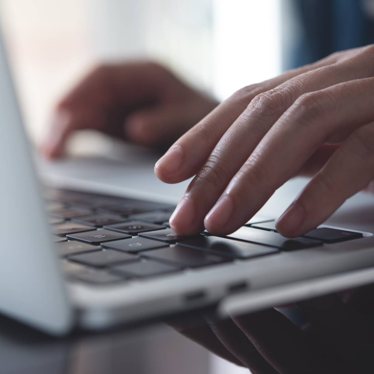 Hands typing on a laptop keyboard; close-up view.