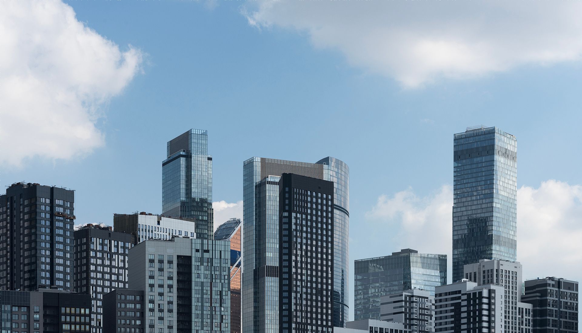 A city skyline with a blue sky and clouds in the background.