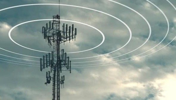 A telephone tower with a lot of antennas against a cloudy sky.