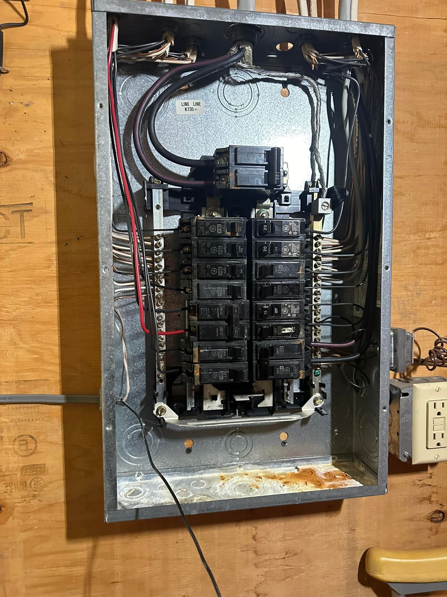 A dirty electrical box is hanging on a wooden wall.