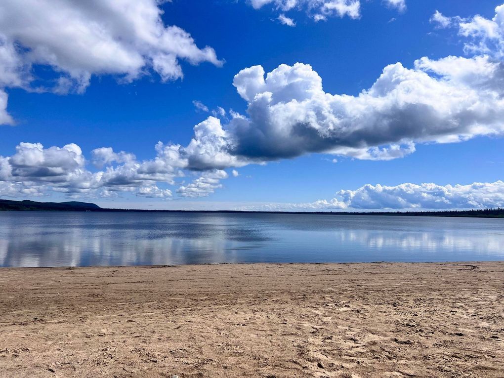 A beach with a lake in the background and clouds in the sky