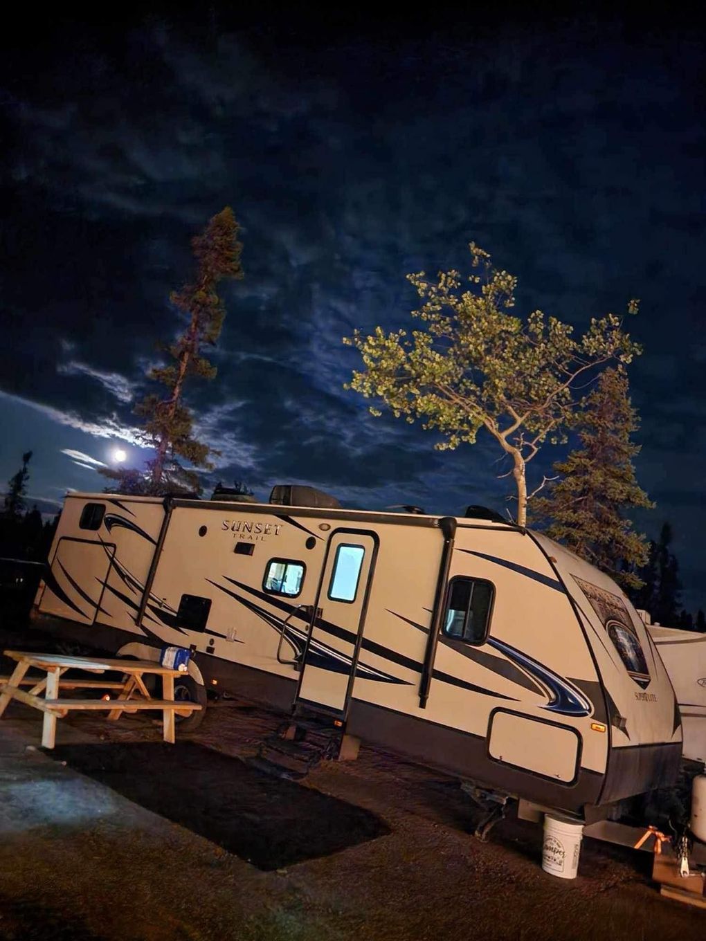 A rv is parked in a campground at night.