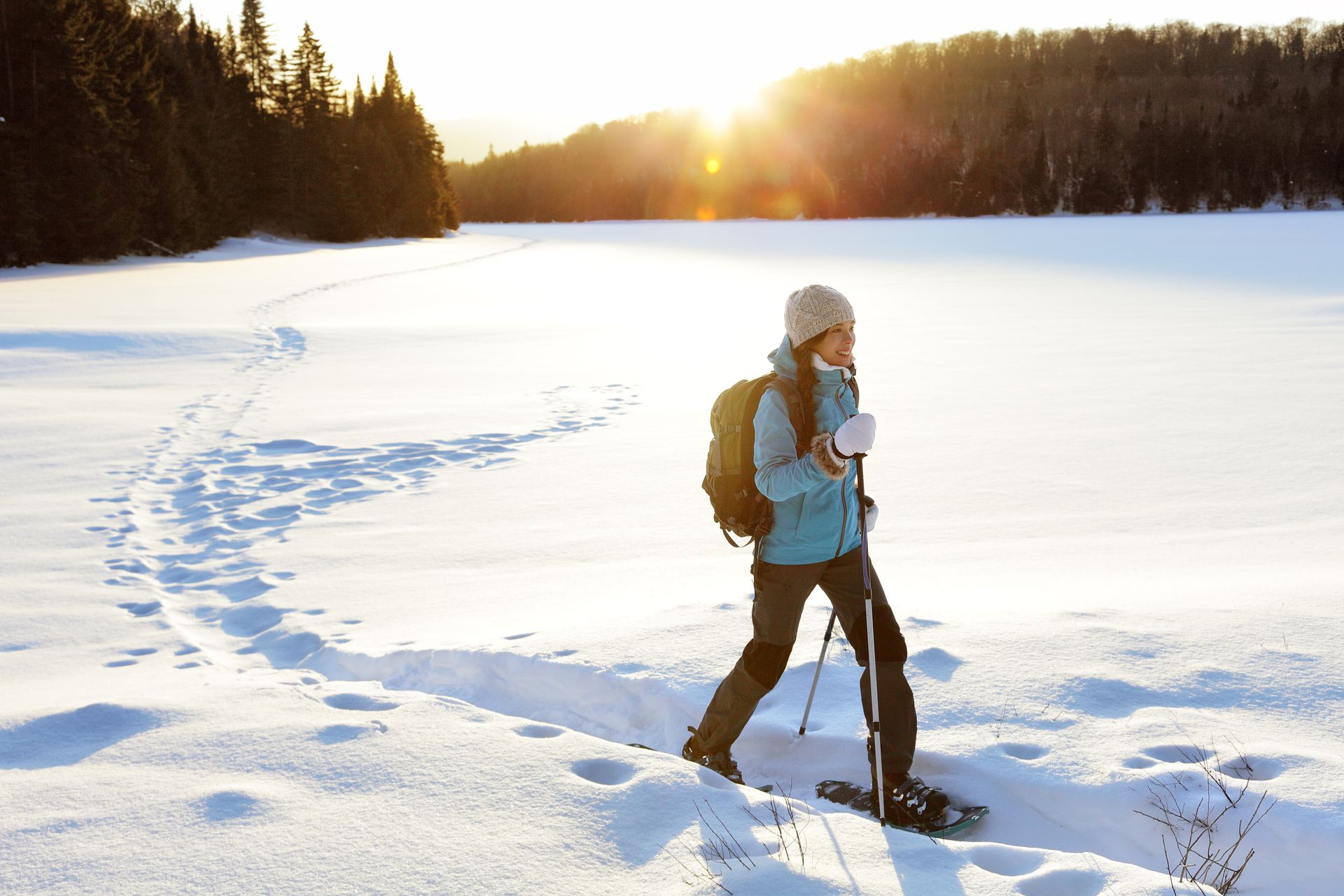 A person is walking through a snowy field with snowshoes.