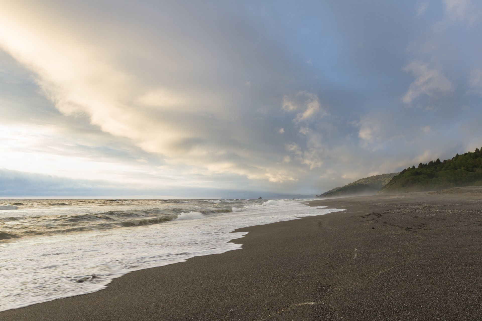 A beach with waves coming in on a cloudy day