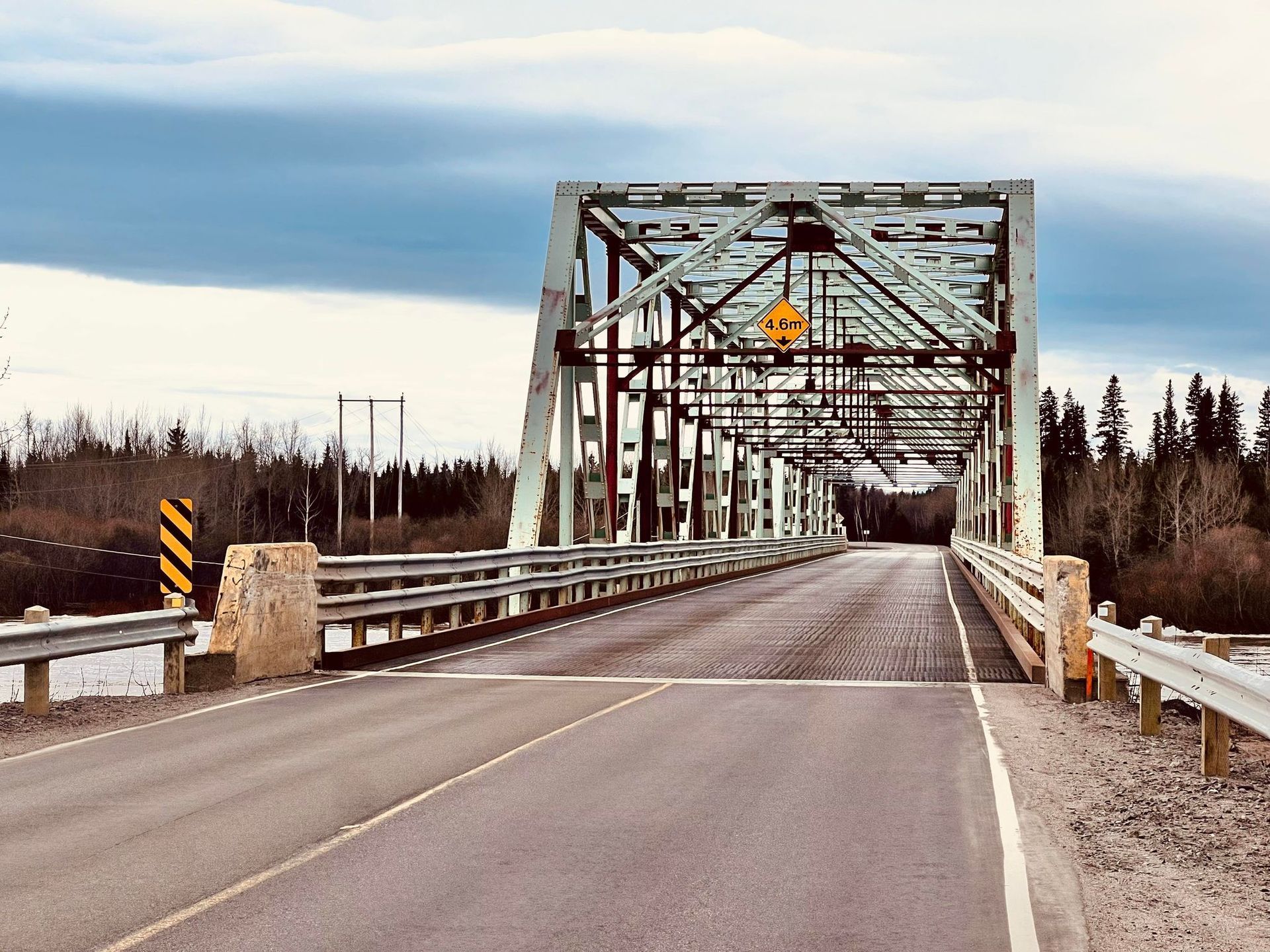 A bridge over a road with a yellow sign on it.