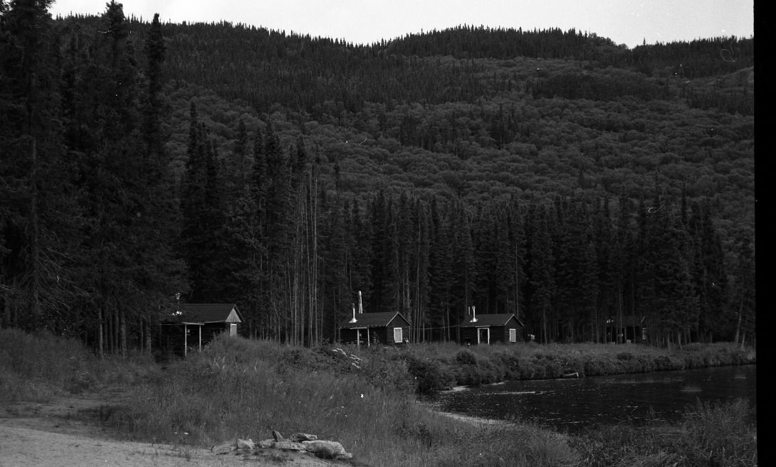 A black and white photo of a house in the middle of a forest.