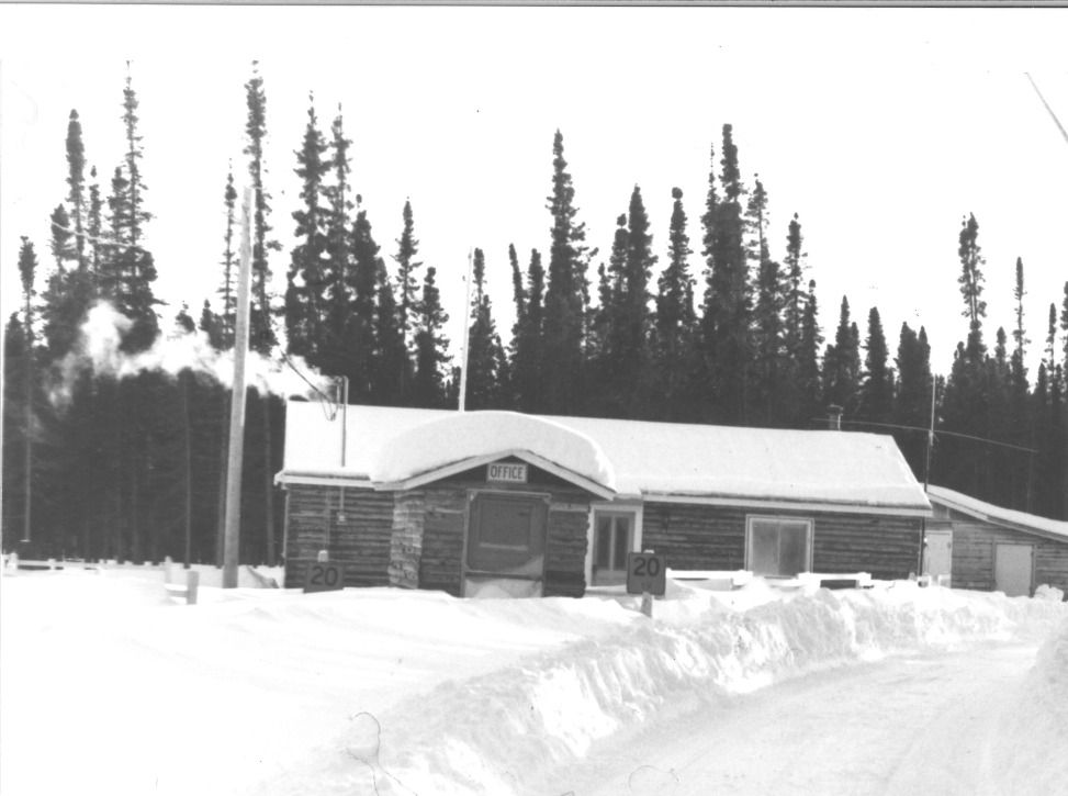 A black and white photo of a log cabin in the snow