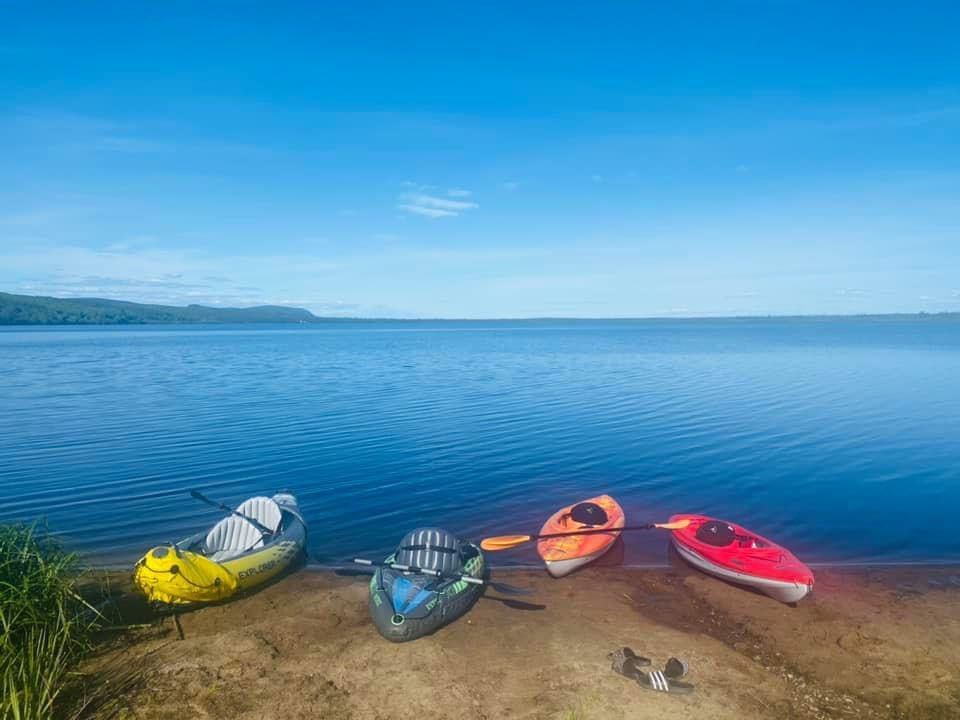 Three kayaks are sitting on the shore of a lake.
