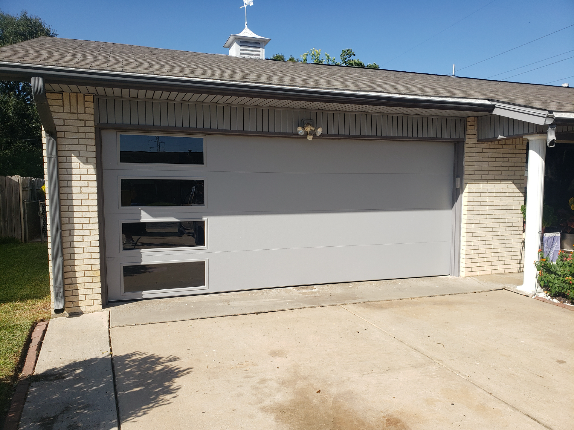 A white garage door is sitting in front of a brick house.