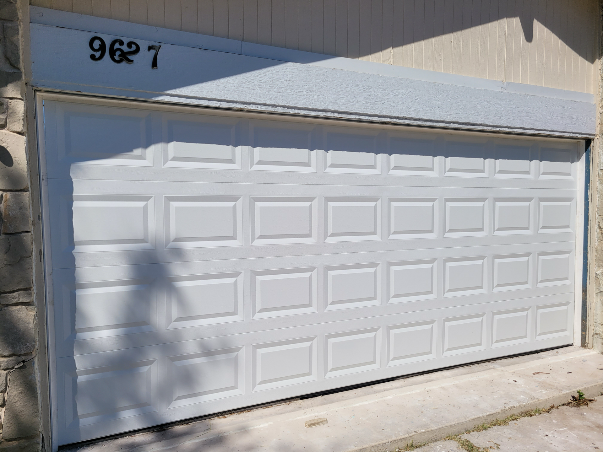 A white garage door is sitting on the side of a house.