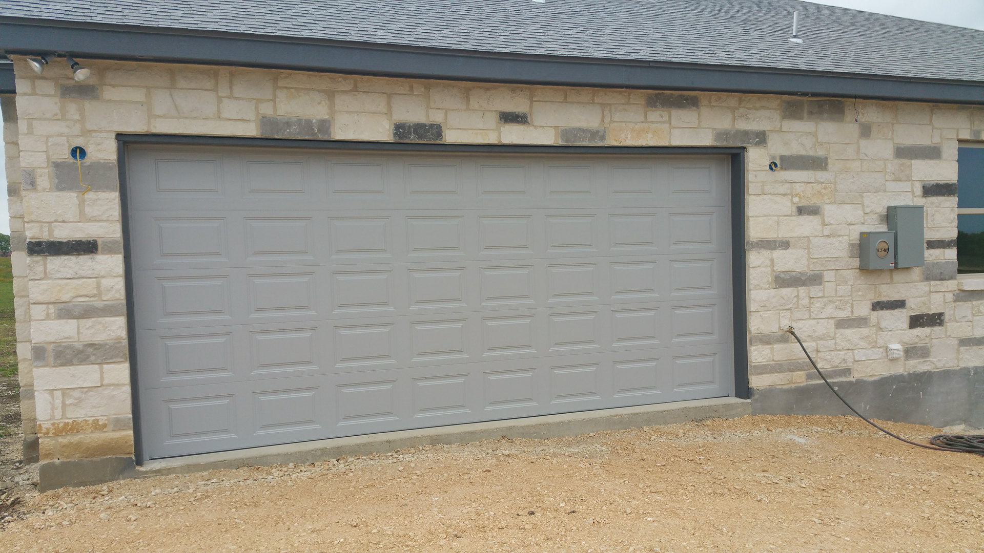 A white garage door is sitting on the side of a brick building.