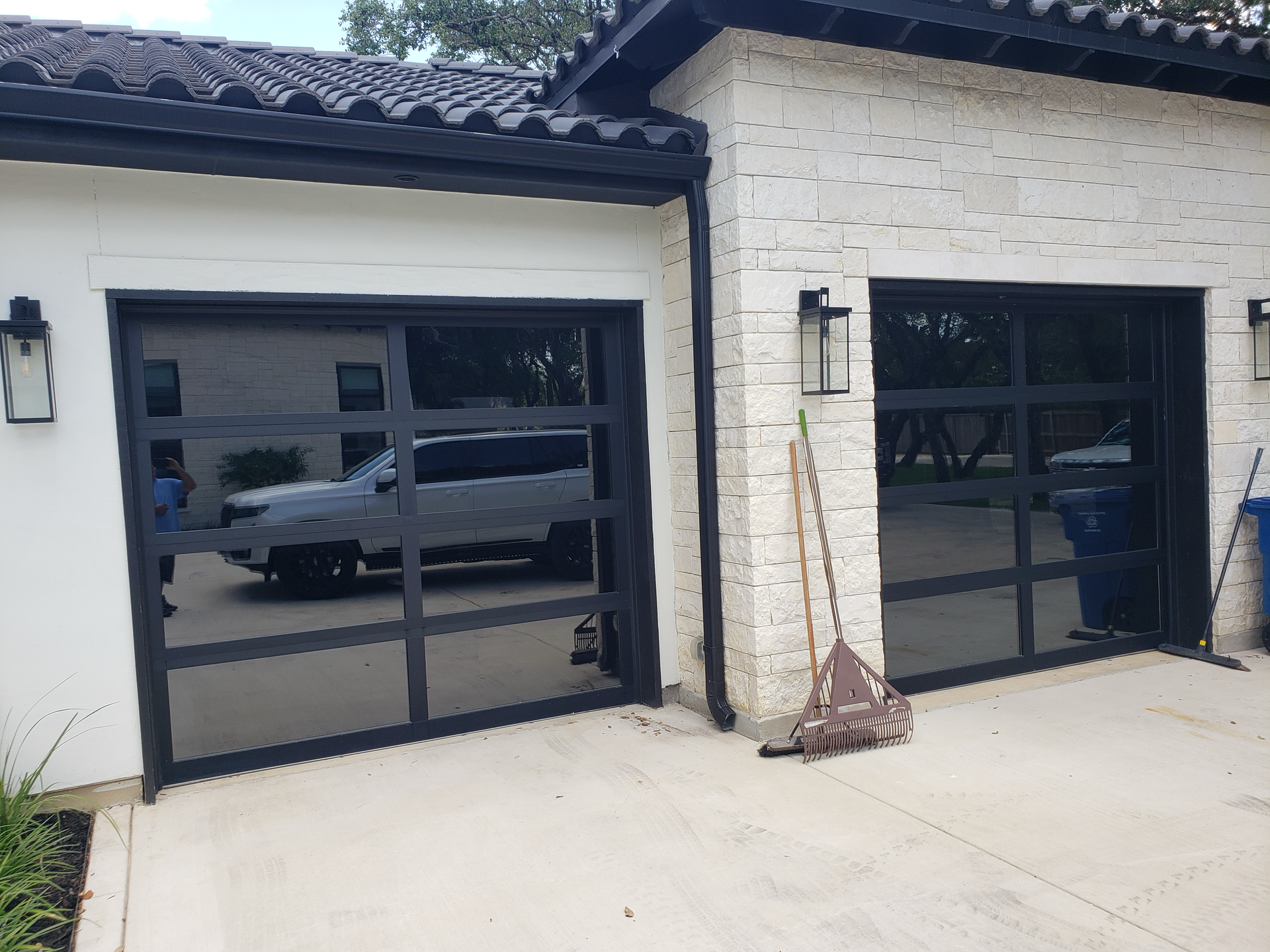 A white house with a black garage door and a car parked in front of it.