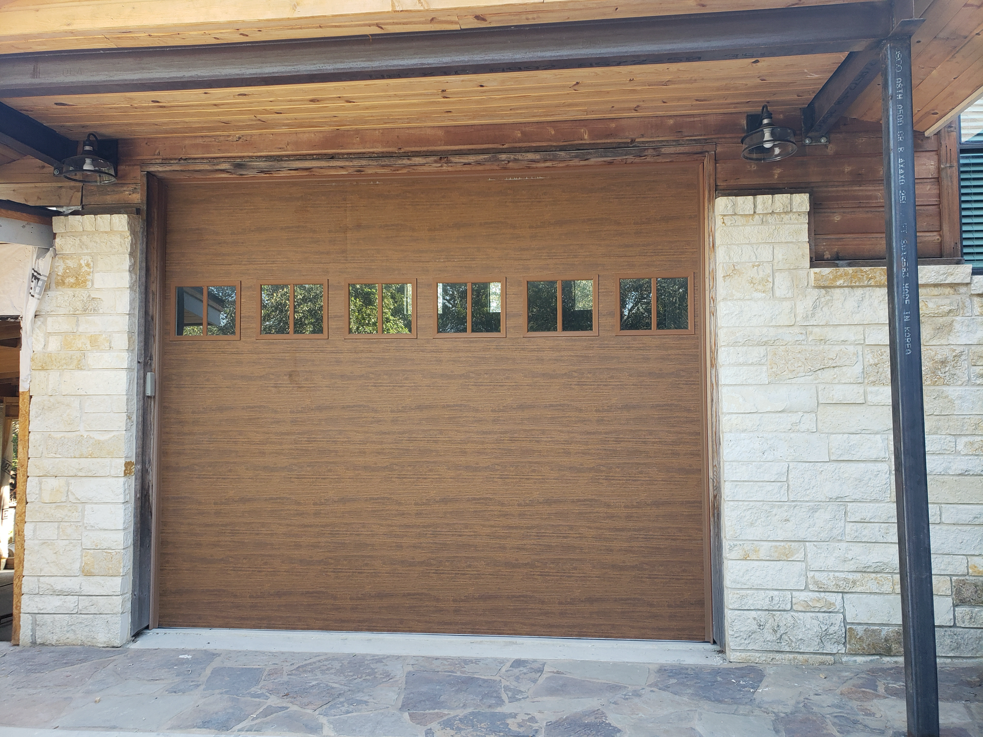 A wooden garage door with a brick wall behind it