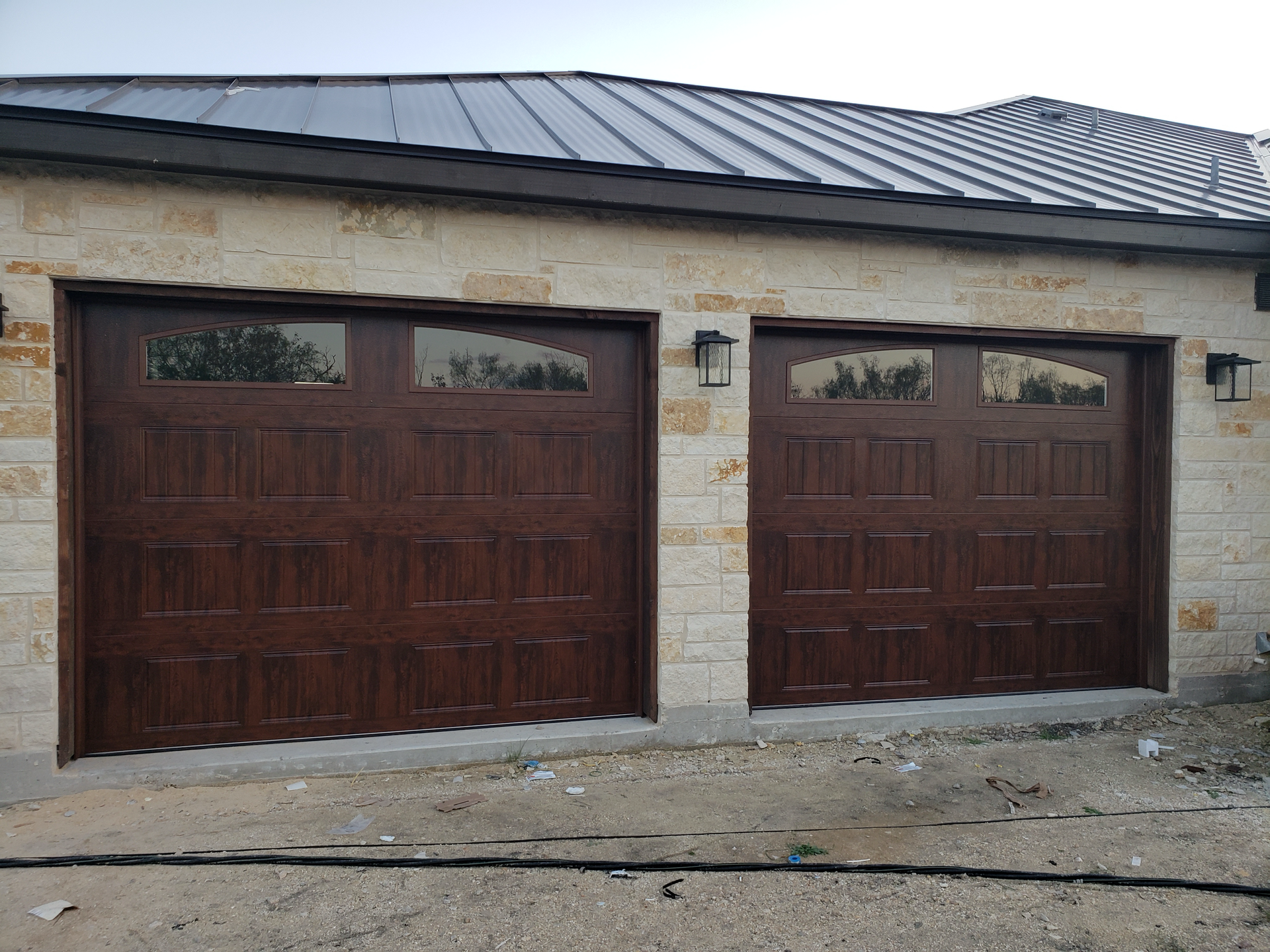 There are two garage doors on the side of a house.