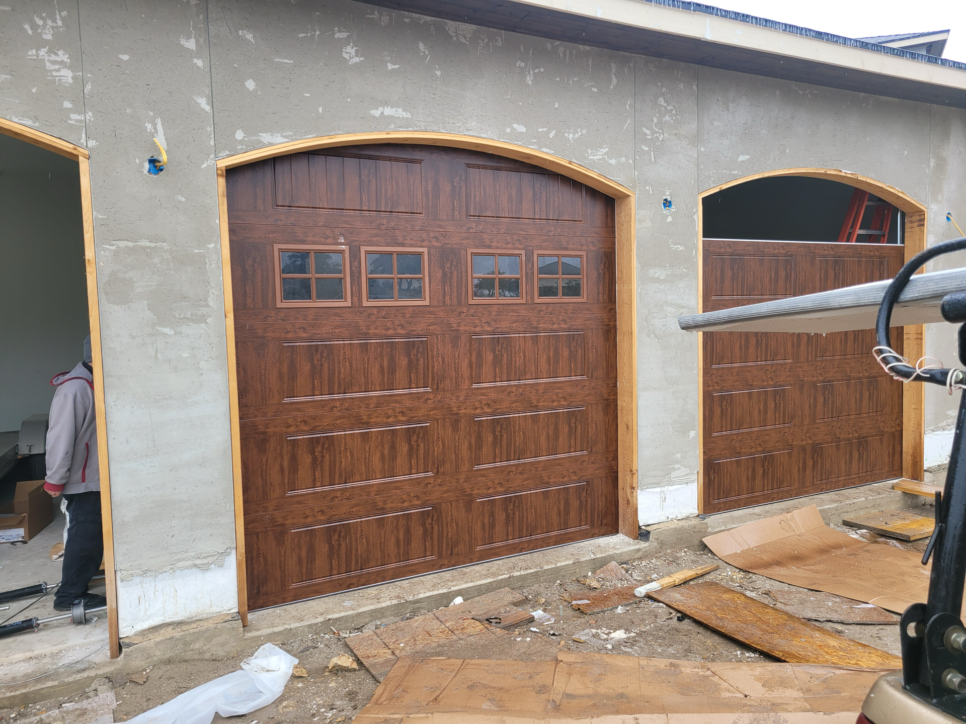 A man is standing in front of a garage door that is being installed.