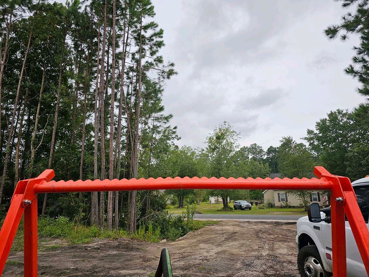 A white truck is parked in a field with trees in the background.