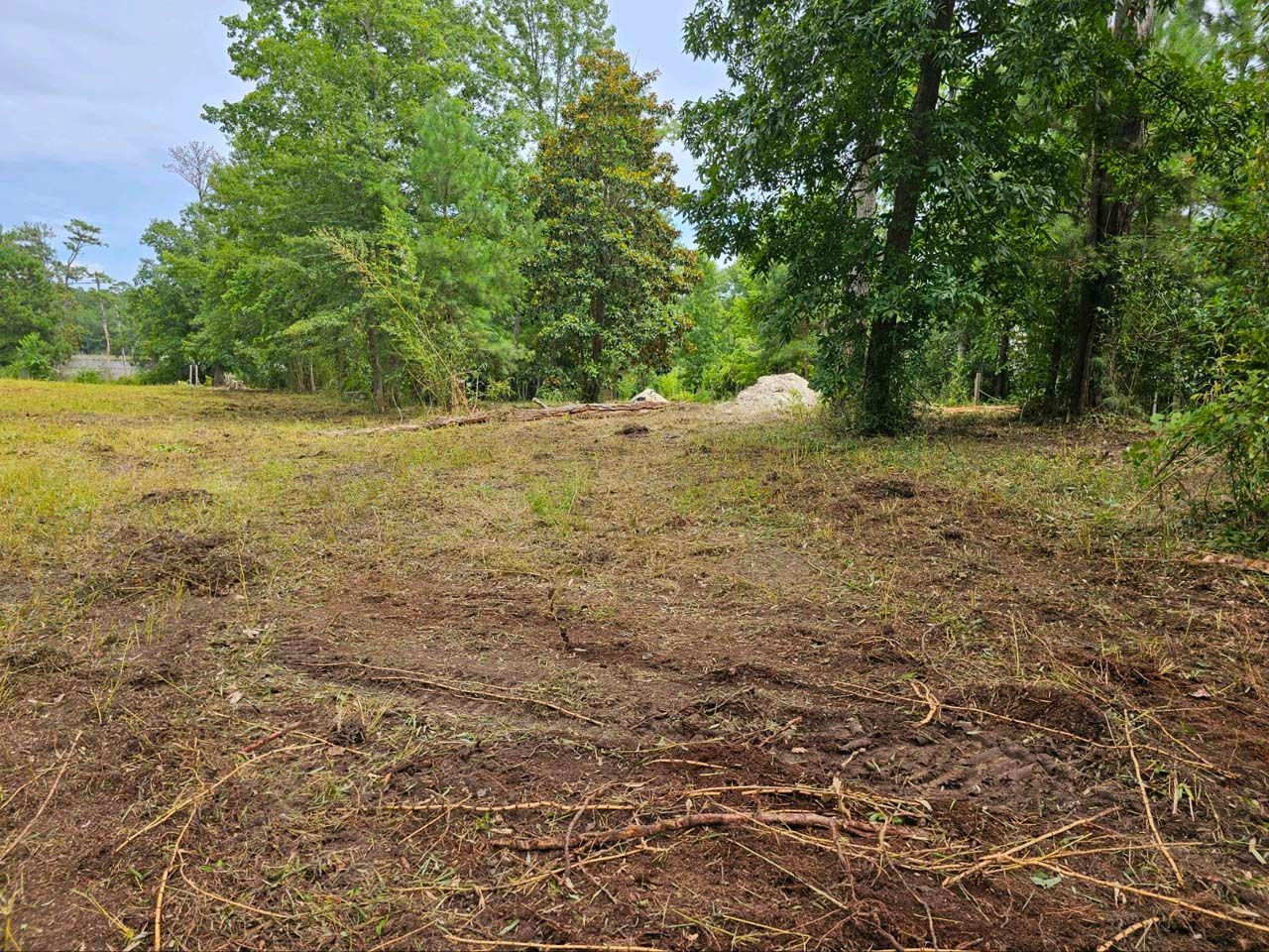 There is a lot of dirt in the middle of a field with trees in the background.