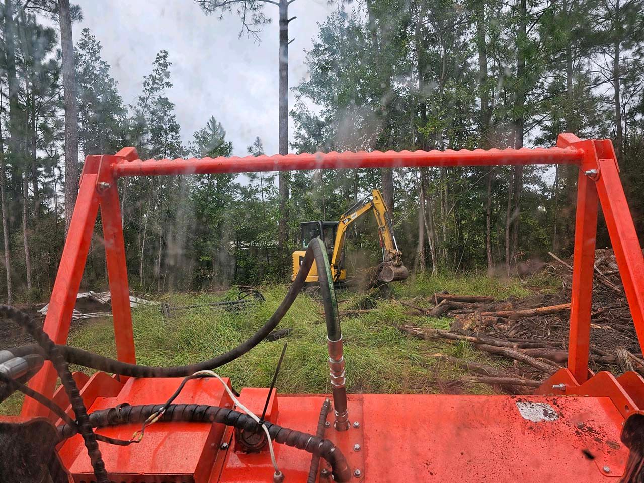 A large orange machine is sitting in a field with a yellow excavator in the background.