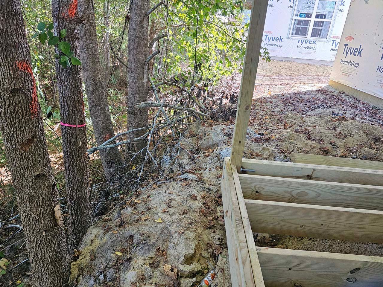 A wooden deck is being built in the woods next to a house.