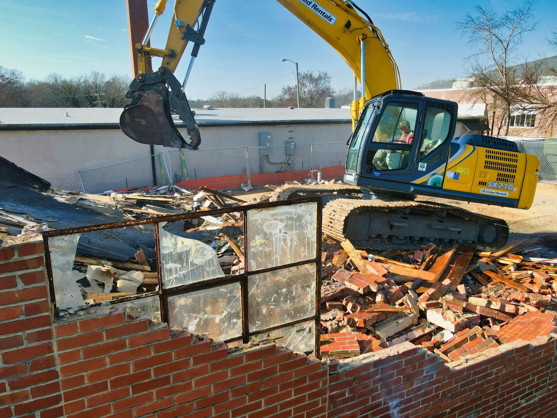 A yellow volvo excavator is working on a dirt hill