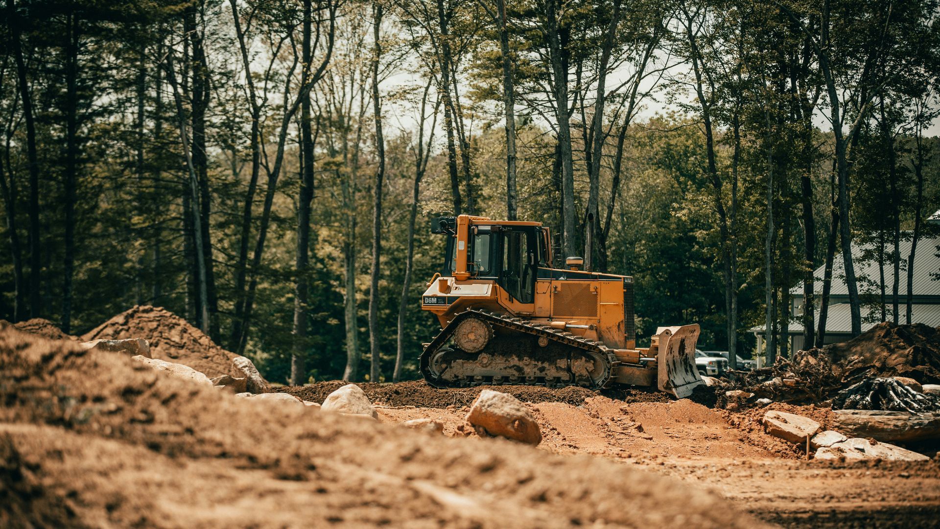 A yellow cat excavator is driving through a dirt field.