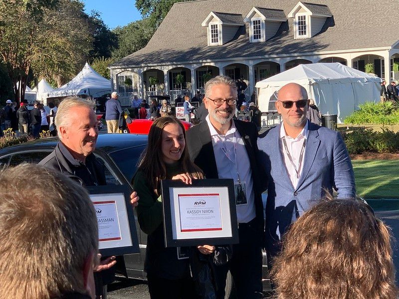 A group of people are standing in front of a house holding plaques.