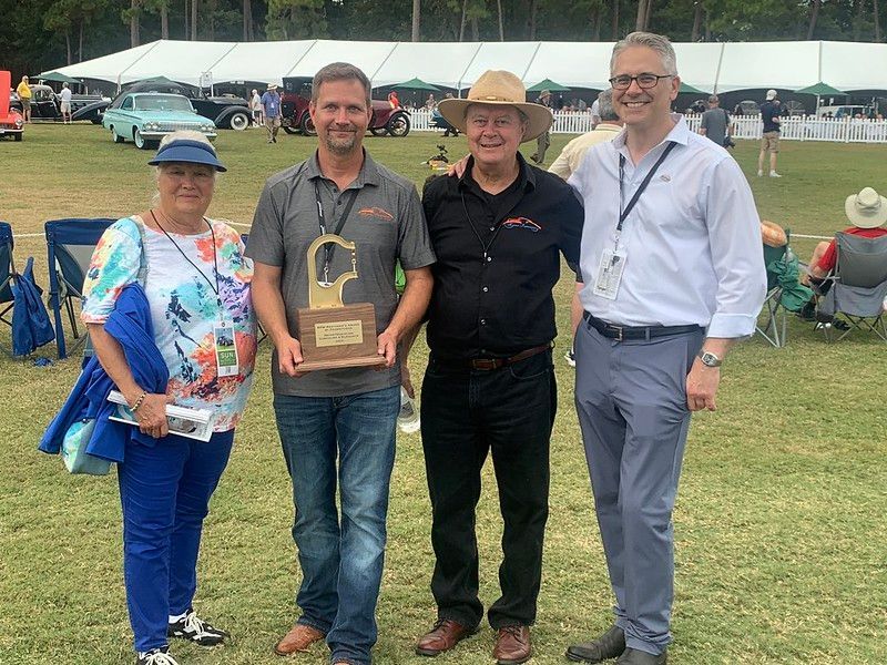 A group of people standing next to each other in a field holding a trophy.