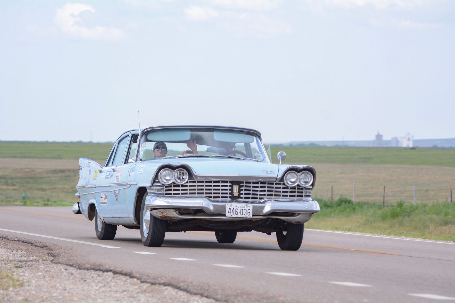 An old car is driving down a country road.