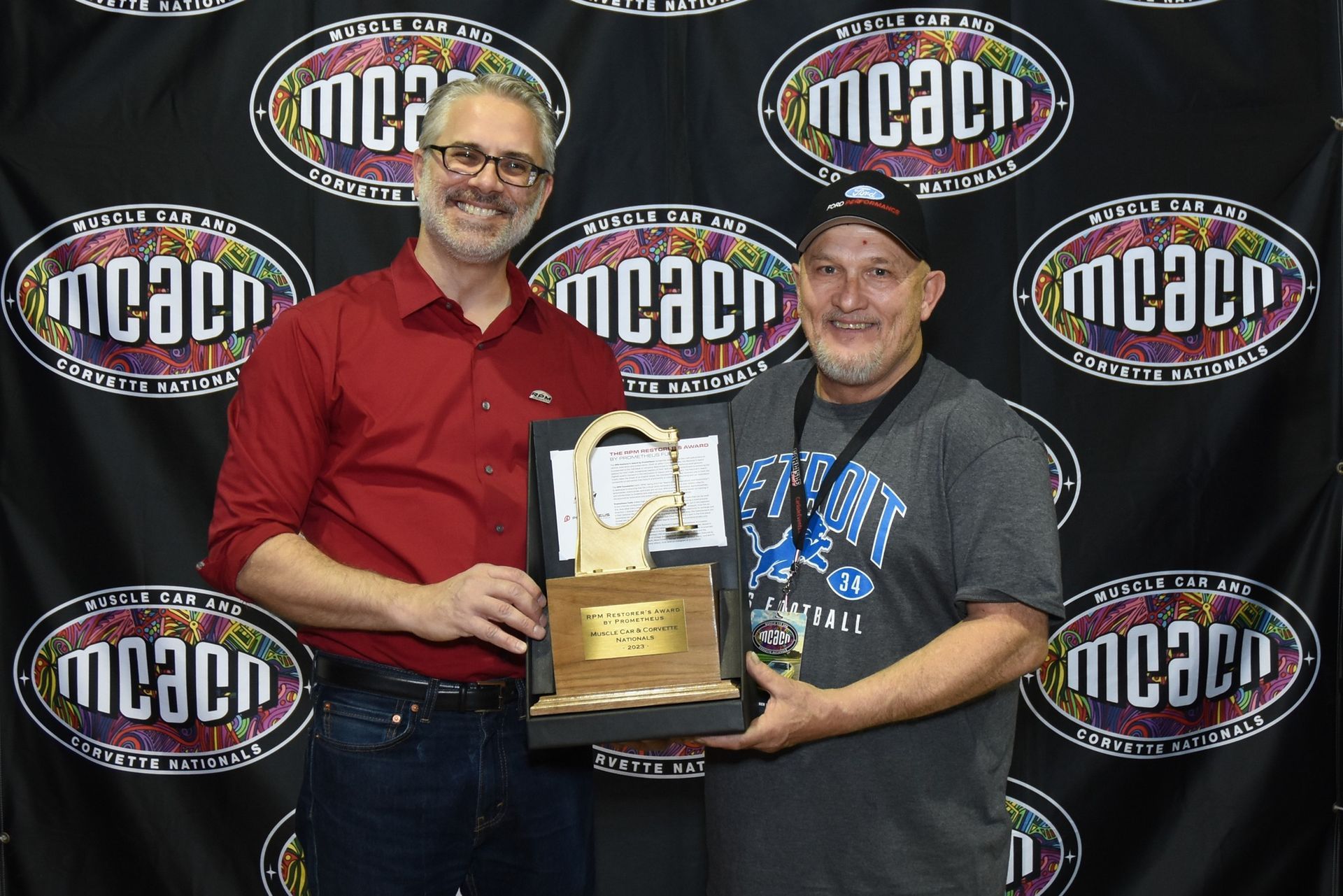 Two men are standing next to each other holding a trophy.