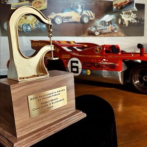 A trophy in front of a red porsche race car