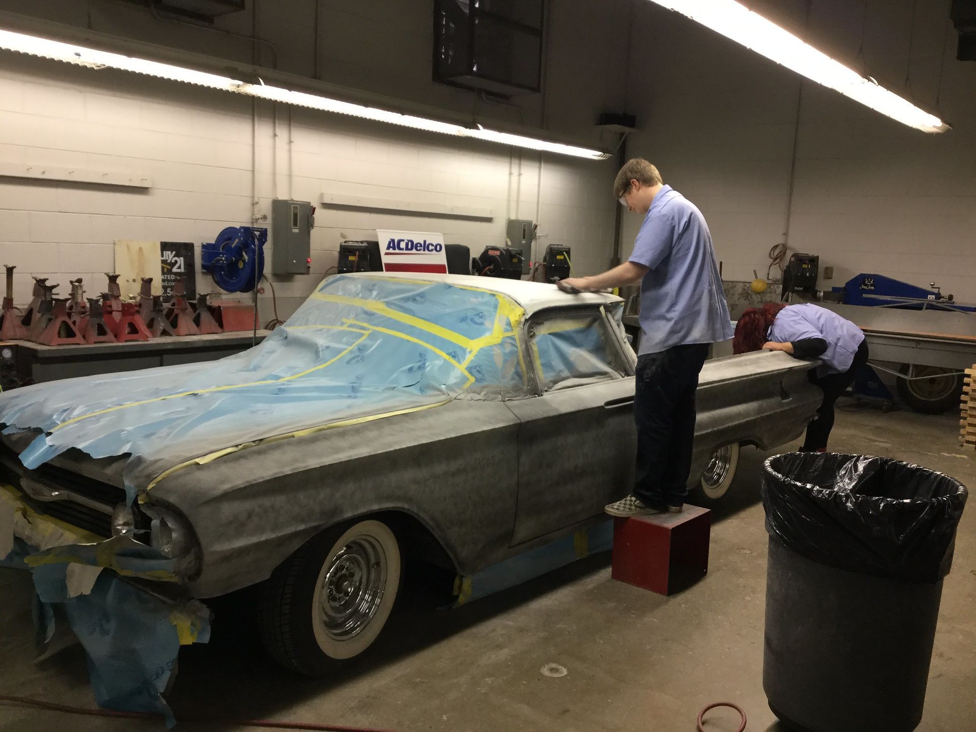 Two men are working on a car in a garage.