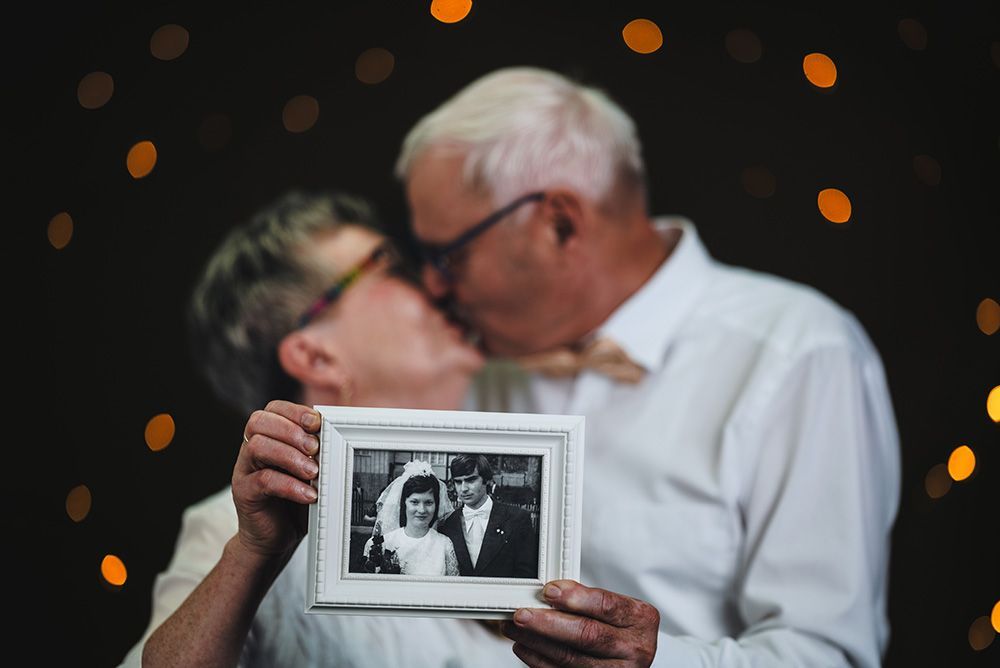 Das Goldpaar zeigt sein altes Hochzeitsfoto und küsst sich dabei