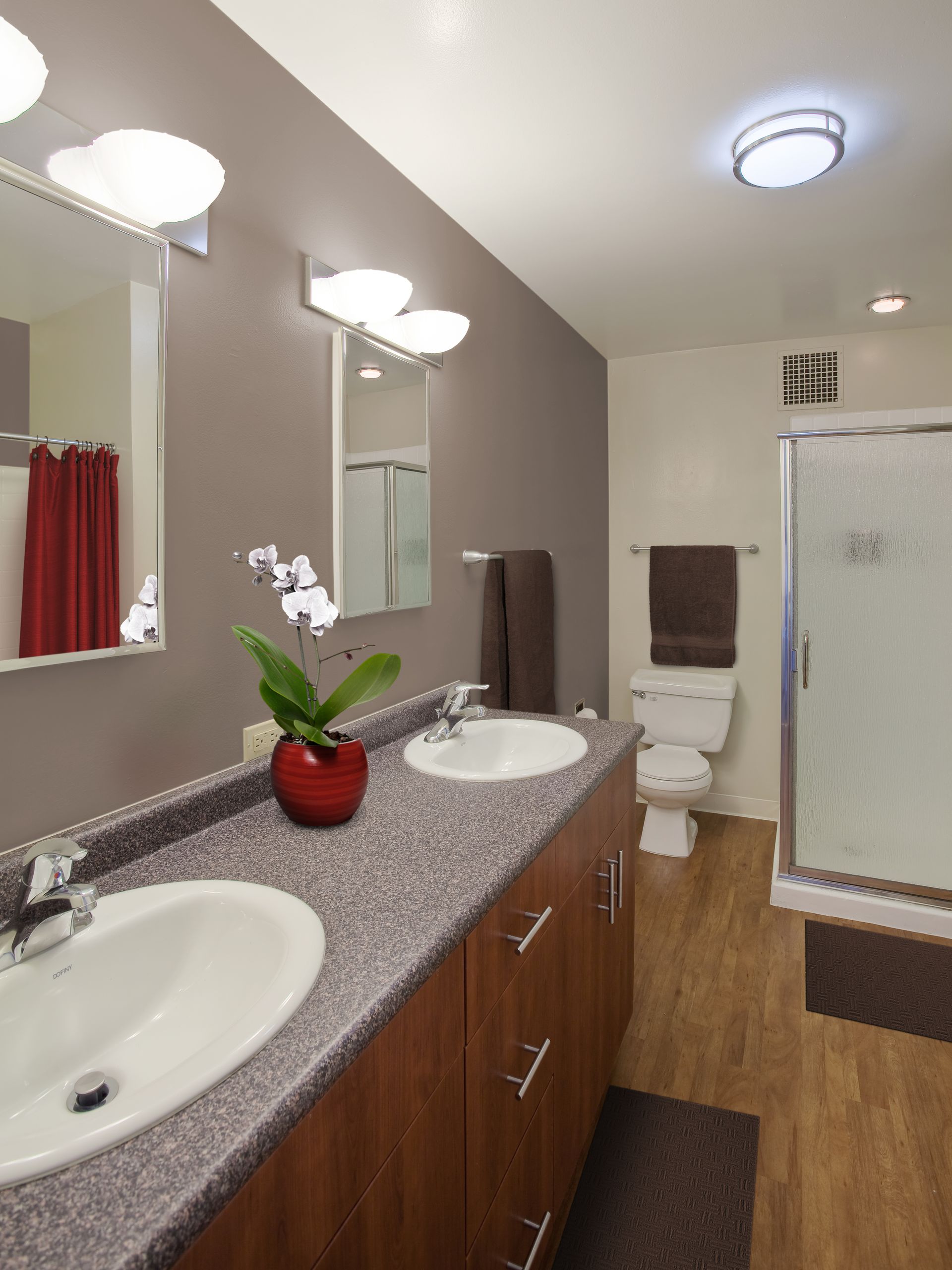 Modern bathroom with double vanity, two mirrors, shower, and toilet.