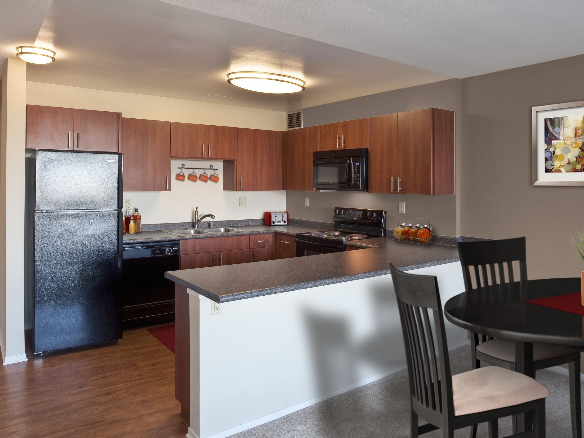 Kitchen with dark wood cabinets, black appliances, and a small dining area.