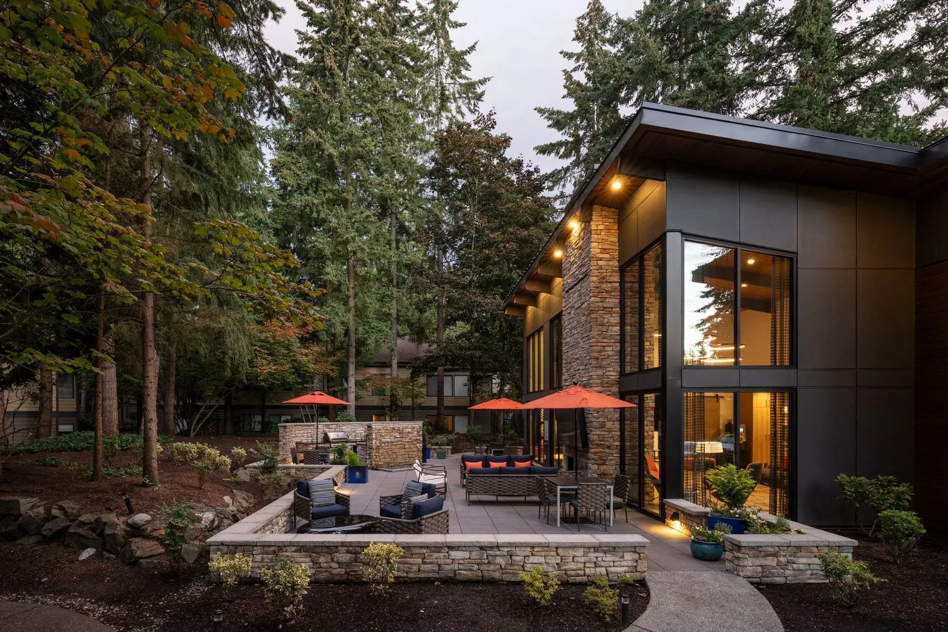 Apartment community outdoor lounge, seating area, grilling station, and nature view.