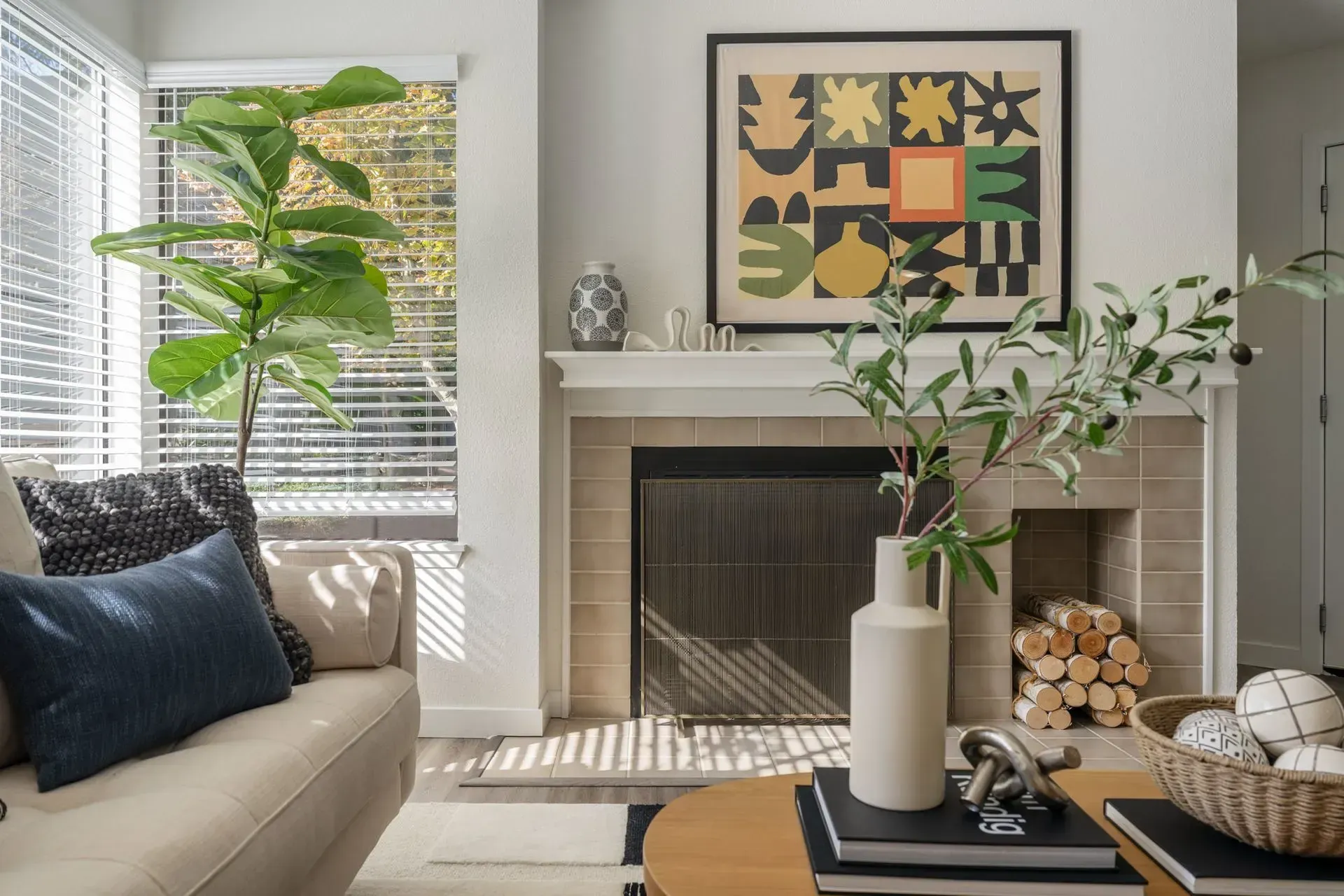 Apartment living room featuring a sofa, coffee table, fireplace, and window.