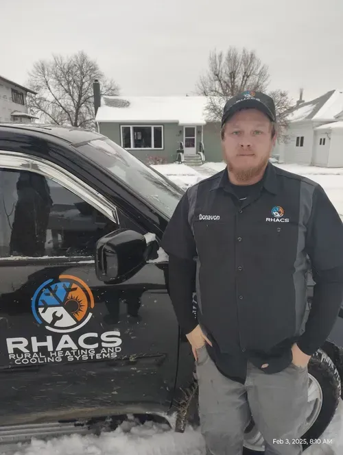 Man in work clothes, standing by black vehicle with logo