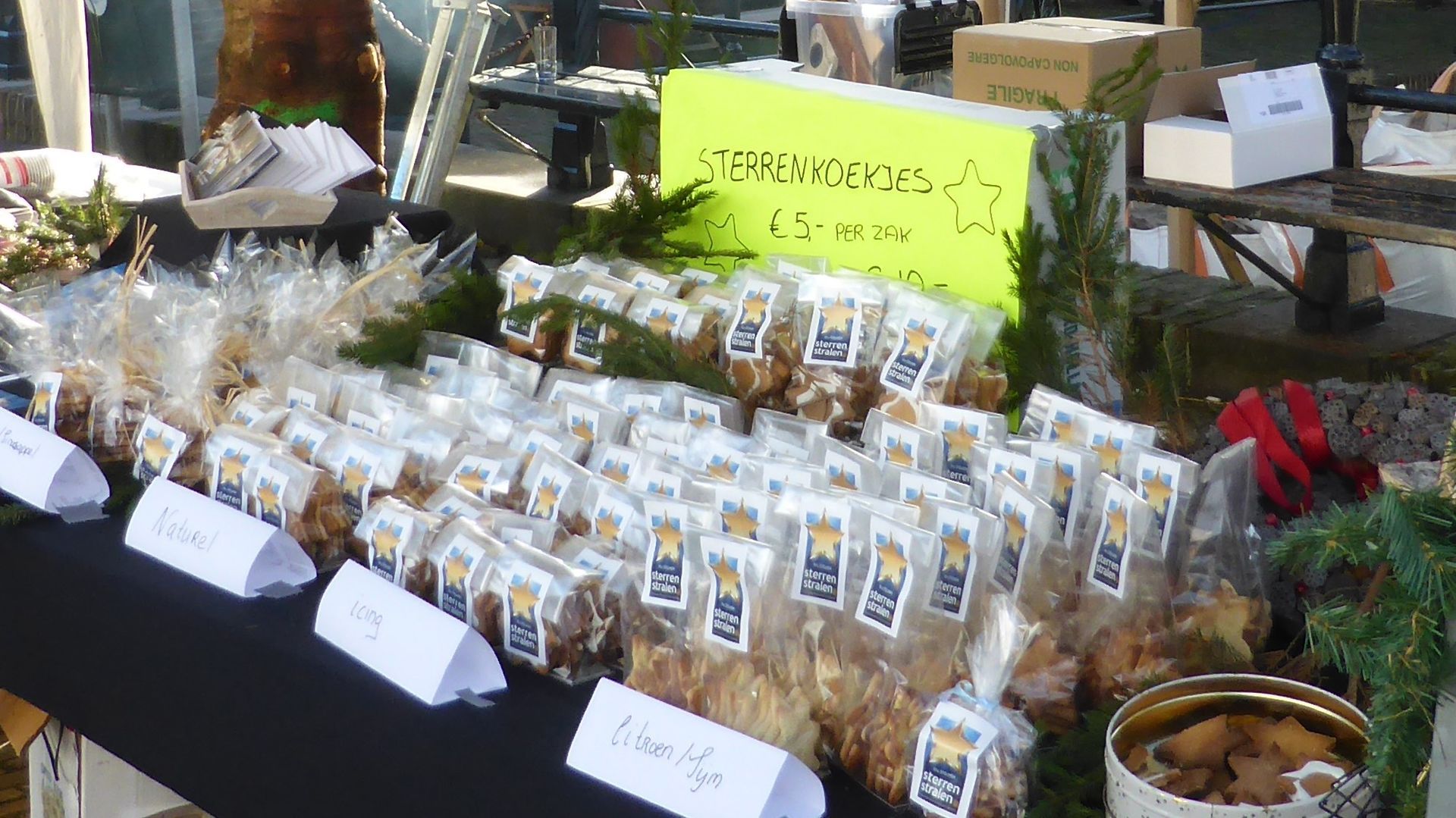 Gebakken producten te koop op een markt; doorzichtige zakken uitgestald, sommige met etiketten.