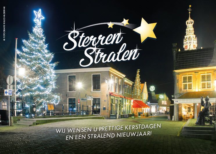 Kersttafereel: een boom, verlichte gebouwen, de tekst 
