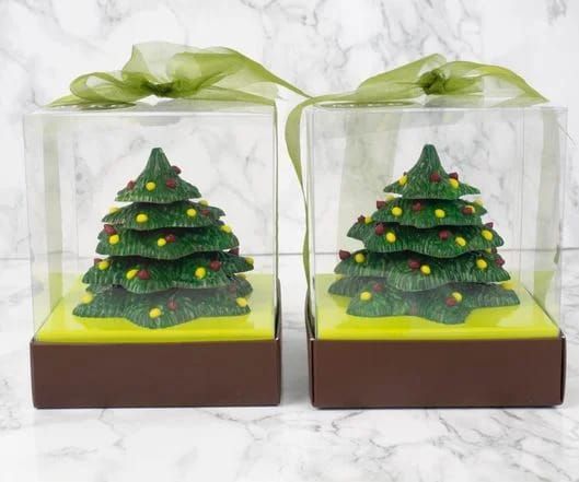 Een koekje in de vorm van een kerstboom met laagjes, versierd met groene snoepjes, op een wit marmeren oppervlak.