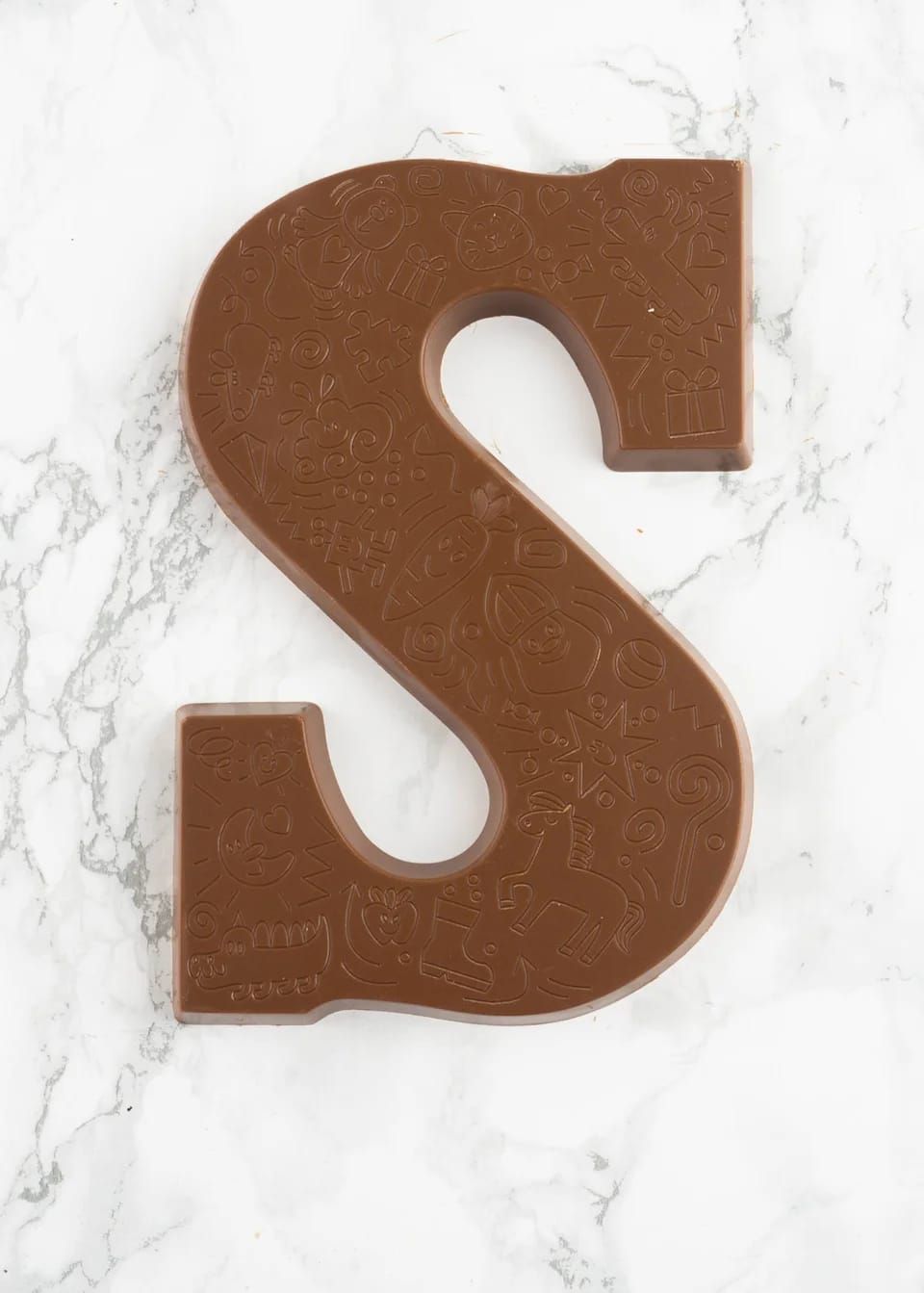 Chocoladeletter "S" op een wit en grijs marmeren oppervlak.