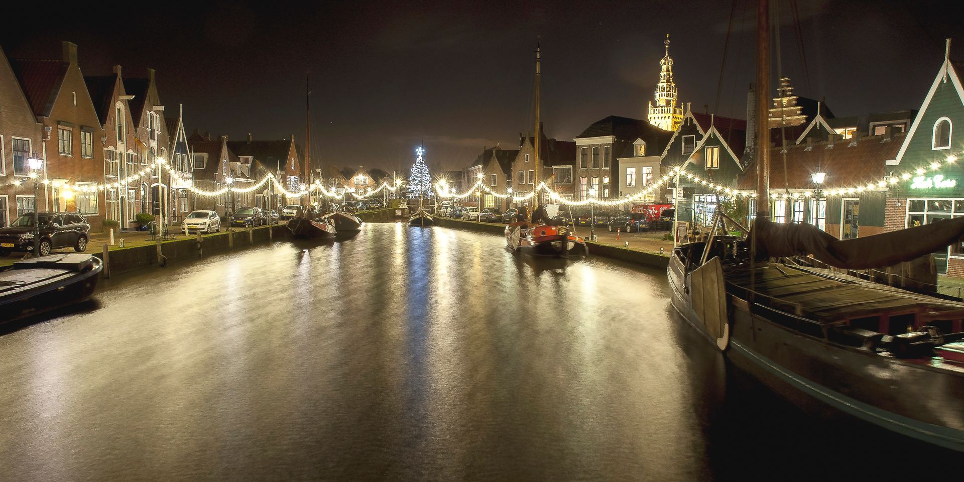 Nachtzicht op een kanaal met verlichte gebouwen en boten, feestelijke verlichting langs het water.