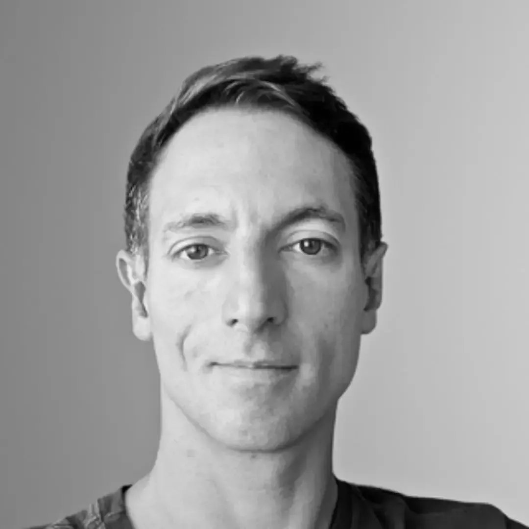 Um homem está sorrindo em uma foto em preto e branco.