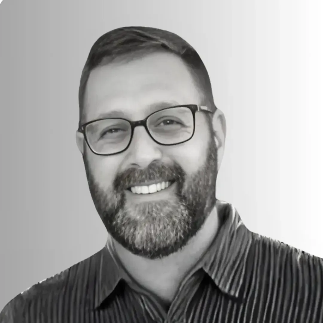 Um homem está sorrindo em uma foto em preto e branco.