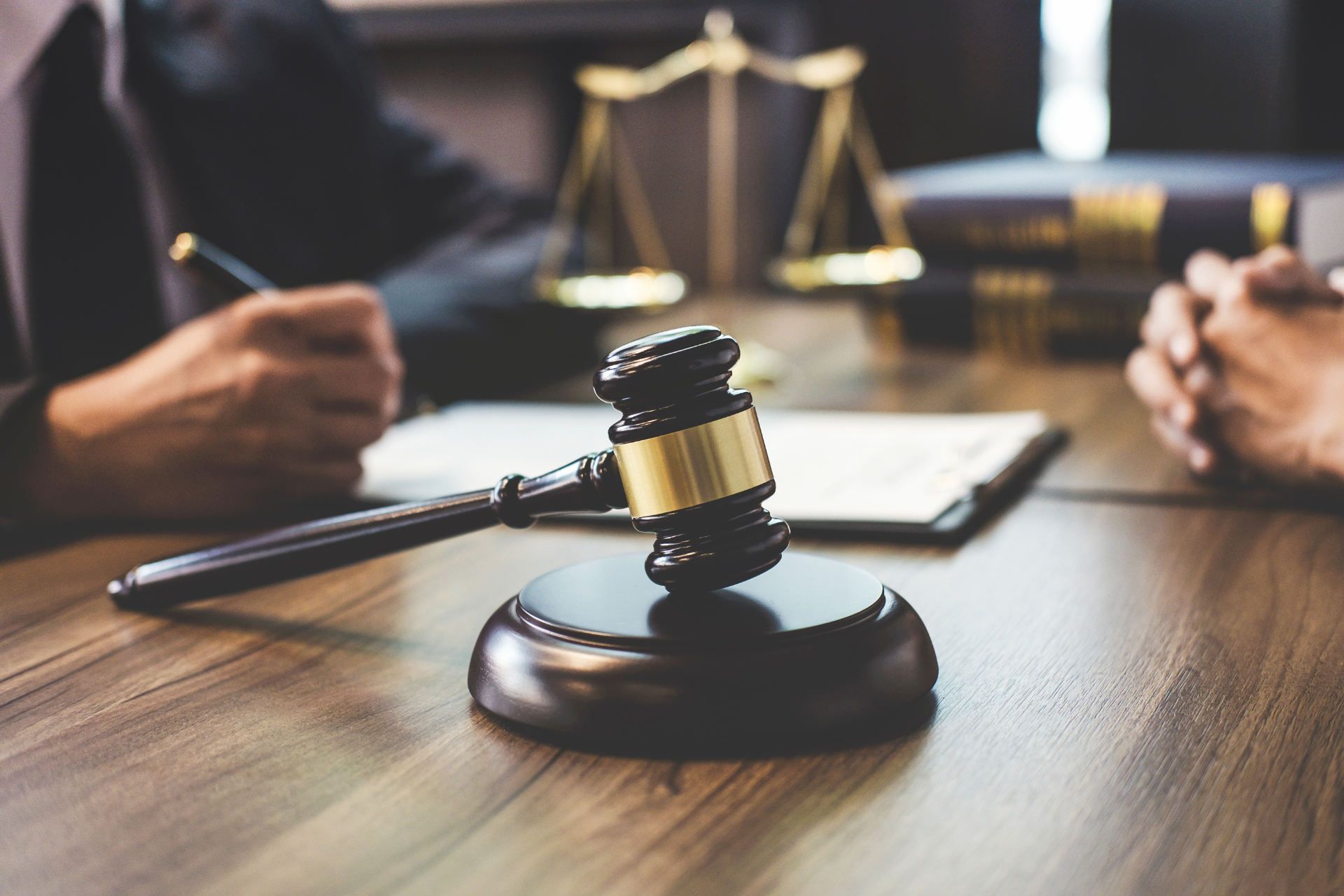 A judge 's gavel is sitting on a wooden table next to a scale of justice.