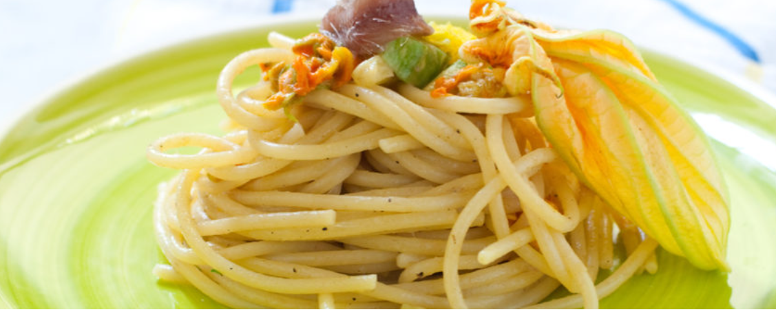 un piatto verde condito con spaghetti e verdure.