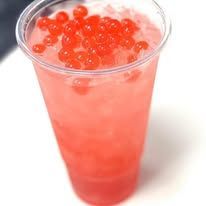 Tall glass of pink drink topped with red tapioca pearls
