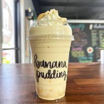 Banana pudding in a clear cup topped with whipped cream on a wooden table