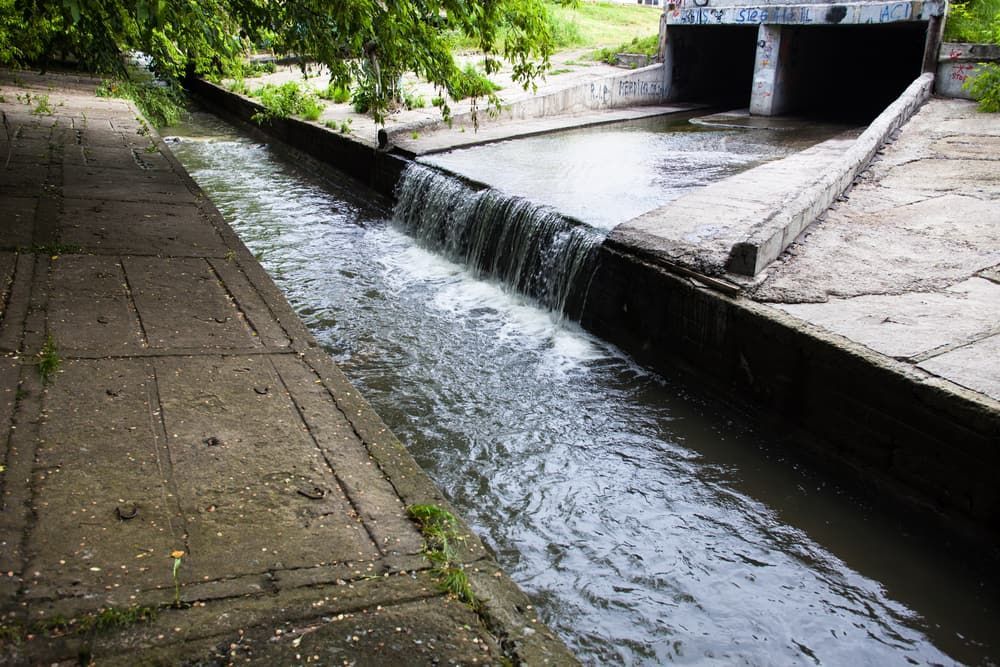 A Small Waterfall is Coming Out of a Drain on a Sidewalk — Tony Gordon Septic Tank Cleaning in Newee Creek, NSW