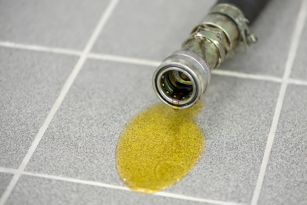 A Hose With Oil Leaking Out of It is on a Tiled Floor — Tony Gordon Septic Tank Cleaning in Newee Creek, NSW